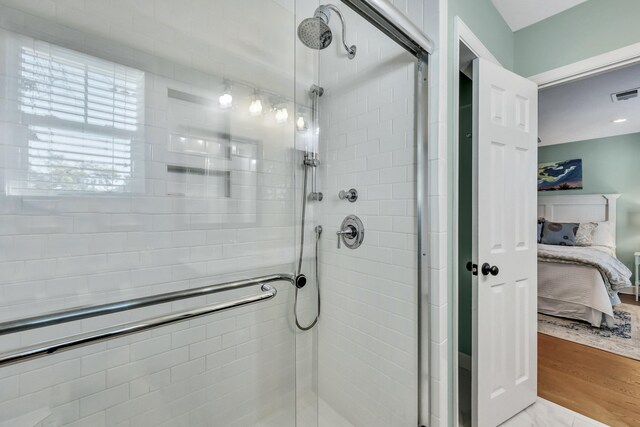 bathroom with wood-type flooring and a shower with shower door