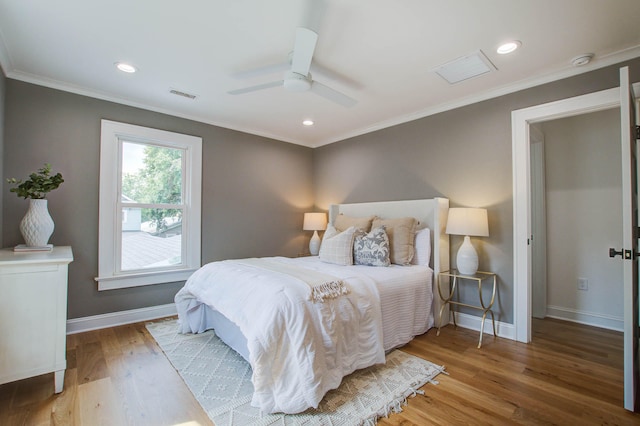 bedroom with ornamental molding, wood finished floors, visible vents, and baseboards