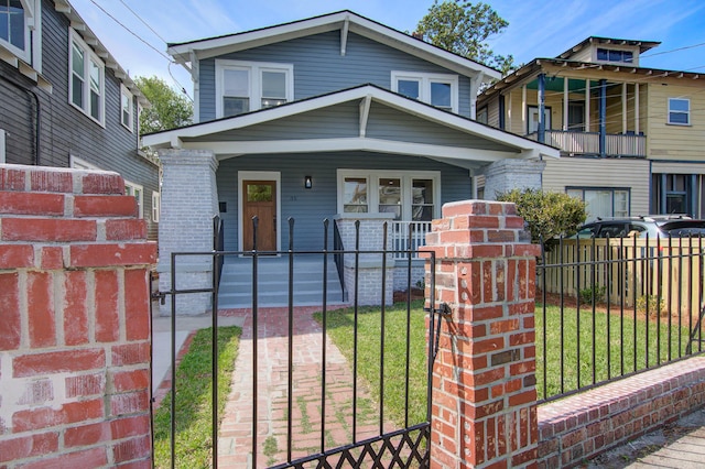 american foursquare style home with brick siding, a fenced front yard, a porch, and a front yard