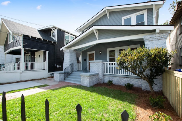 view of front of property with covered porch, fence, and a front lawn