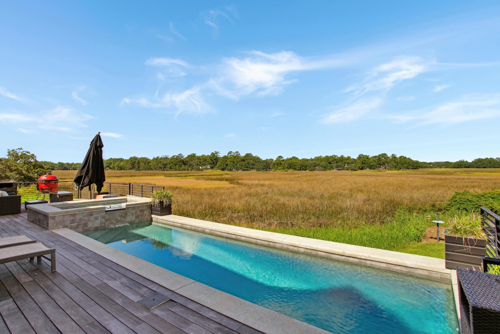 view of swimming pool featuring a rural view, an in ground hot tub, and a wooden deck