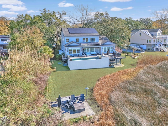 rear view of property with solar panels, a patio, and a yard