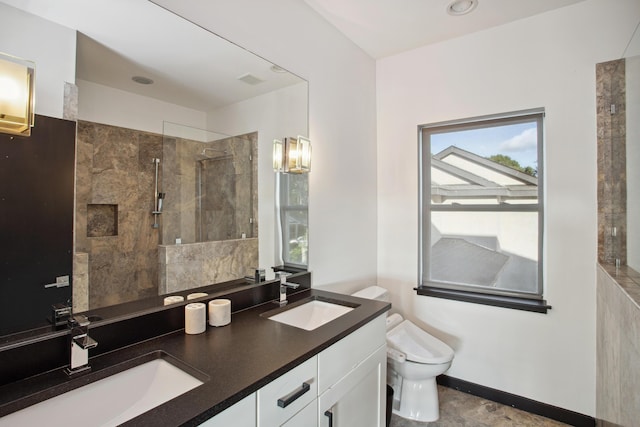 bathroom with toilet, a tile shower, a healthy amount of sunlight, and vanity