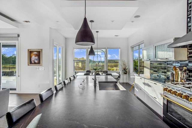 kitchen featuring hanging light fixtures, decorative backsplash, stainless steel range, white cabinets, and sink