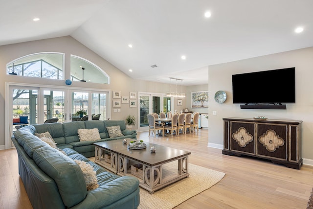 living room with light hardwood / wood-style floors, high vaulted ceiling, and french doors