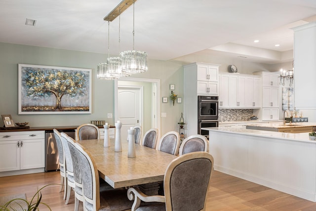 dining space with a notable chandelier, light wood-type flooring, and sink