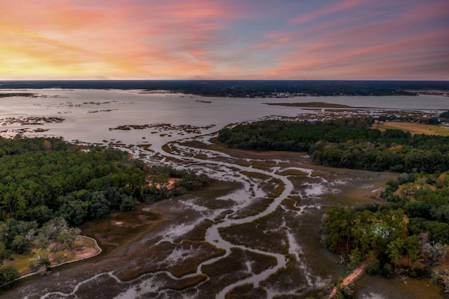 aerial view at dusk featuring a water view