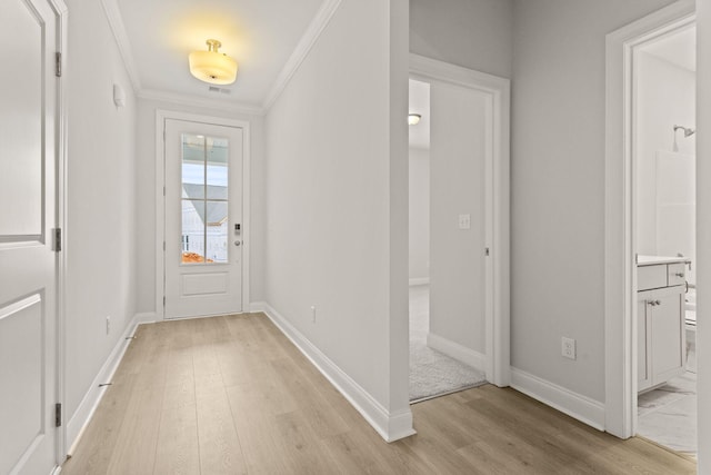 doorway to outside with baseboards, light wood finished floors, crown molding, and visible vents