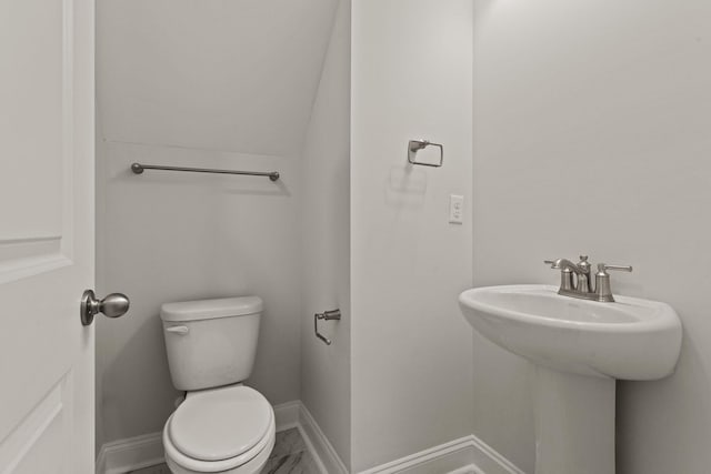 half bathroom with toilet, baseboards, and a sink