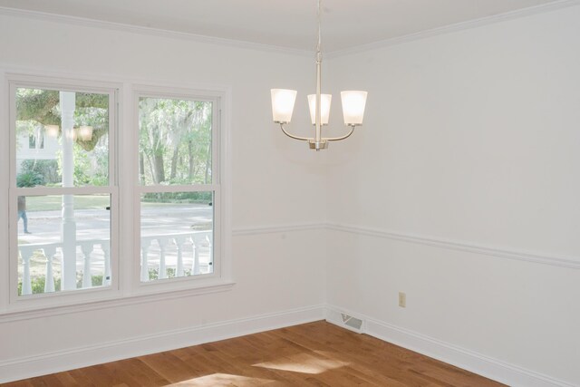 unfurnished dining area with ornamental molding, wood-type flooring, and a notable chandelier