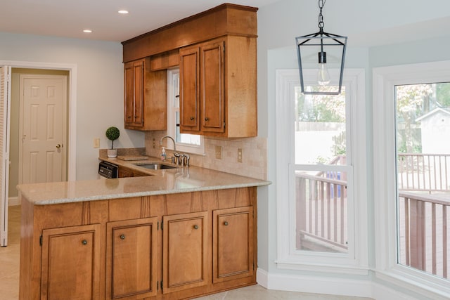 kitchen with kitchen peninsula, backsplash, light stone counters, sink, and pendant lighting