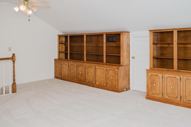 unfurnished living room featuring ceiling fan, light colored carpet, and vaulted ceiling