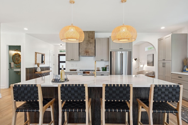 kitchen with gray cabinetry, decorative light fixtures, a kitchen bar, and stainless steel appliances