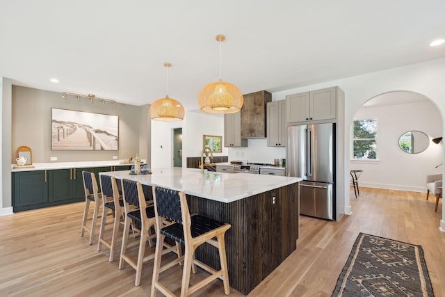 kitchen featuring appliances with stainless steel finishes, light stone counters, decorative light fixtures, light hardwood / wood-style floors, and a large island