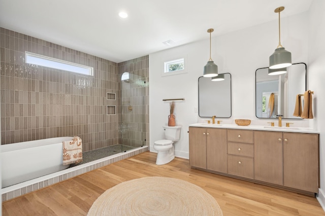 bathroom featuring tiled shower, hardwood / wood-style floors, toilet, and a healthy amount of sunlight