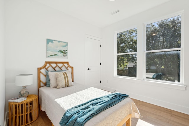 bedroom with hardwood / wood-style floors and multiple windows