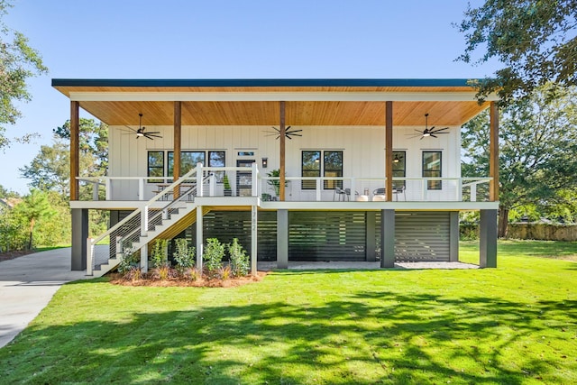 rear view of property featuring a lawn, ceiling fan, and covered porch