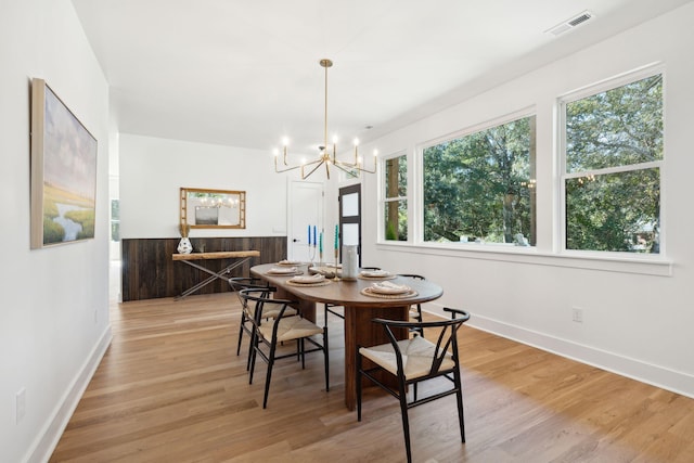 dining area with light wood-type flooring and a notable chandelier