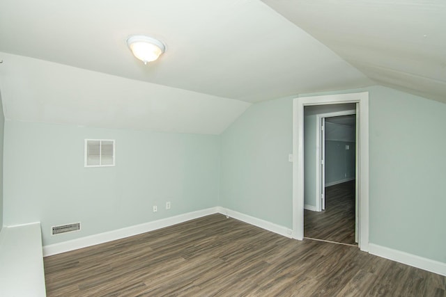 additional living space with dark wood-type flooring and vaulted ceiling