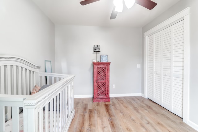 bedroom featuring a closet, a nursery area, light hardwood / wood-style floors, and ceiling fan