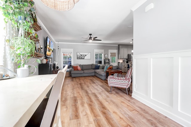 living room featuring light hardwood / wood-style flooring, ceiling fan, and crown molding