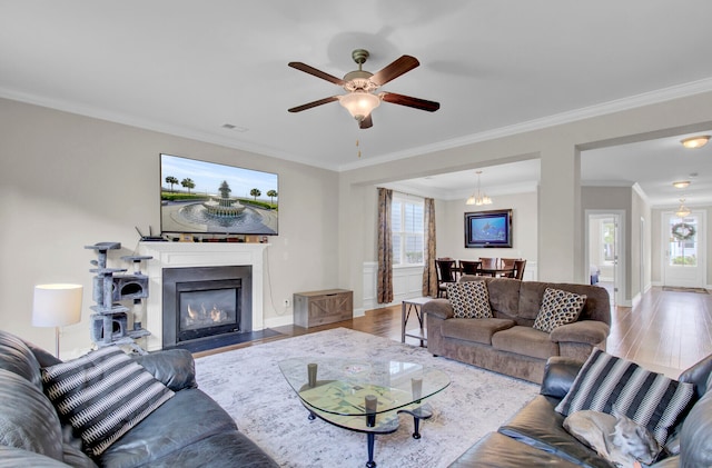 living room featuring hardwood / wood-style floors, crown molding, ceiling fan with notable chandelier, and a wealth of natural light