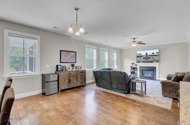 living room featuring ornamental molding, ceiling fan with notable chandelier, and light wood-type flooring