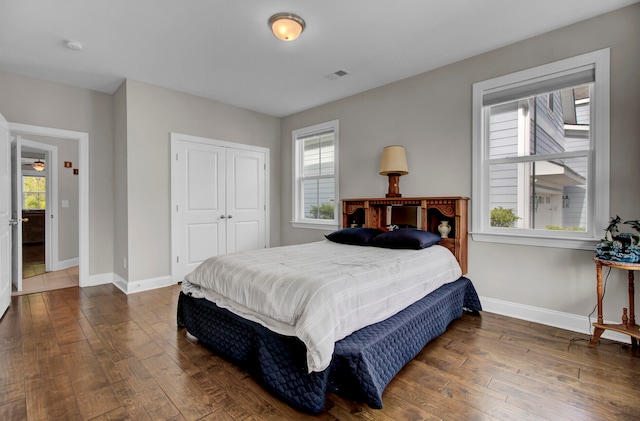 bedroom with dark wood-type flooring, a closet, and multiple windows