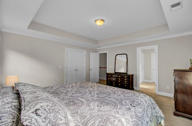 carpeted bedroom with a closet, a raised ceiling, and crown molding