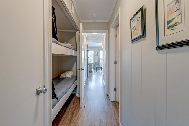 hallway featuring wood finished floors, visible vents, and ornamental molding