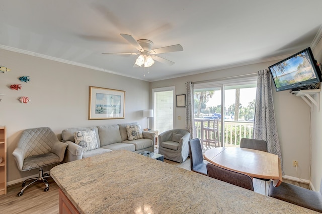 living area featuring baseboards, a ceiling fan, light wood-style flooring, and crown molding