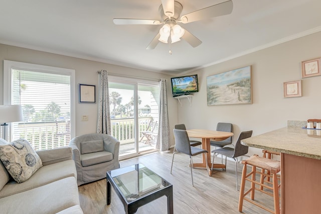 living room with light wood-style flooring, crown molding, and a ceiling fan