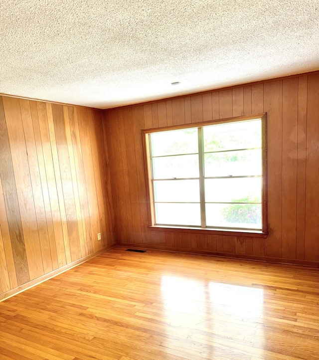 unfurnished room with a textured ceiling, visible vents, and light wood finished floors