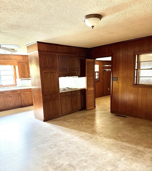 kitchen featuring wooden walls, a textured ceiling, a wealth of natural light, and light countertops