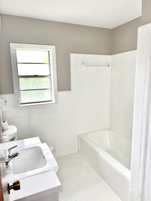 bathroom featuring tile walls, shower / bathtub combination, toilet, a wainscoted wall, and tile patterned flooring
