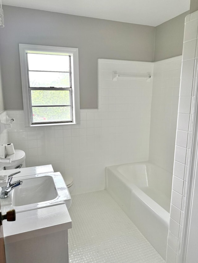 bathroom with tile patterned floors, tile walls, a wainscoted wall, toilet, and vanity