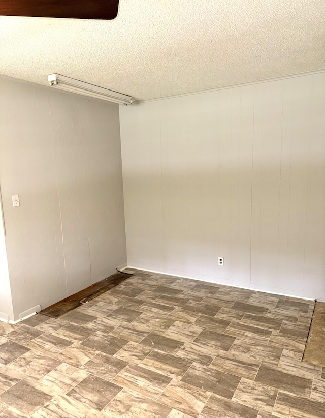 unfurnished room with wood walls and a textured ceiling