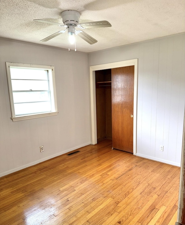 unfurnished bedroom featuring a textured ceiling, visible vents, and light wood-style flooring