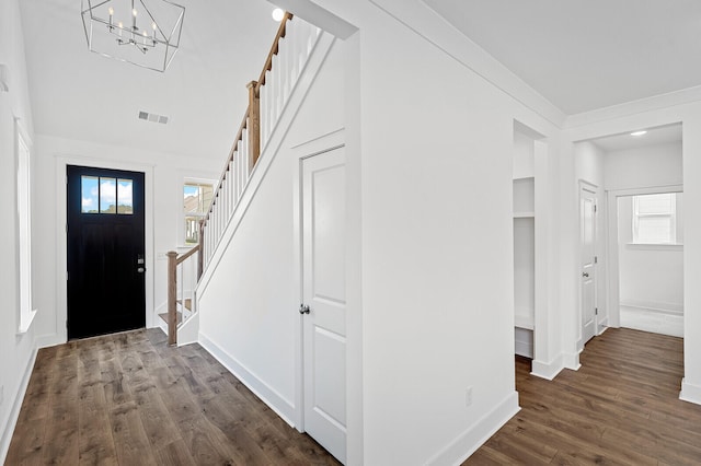 entryway with dark hardwood / wood-style flooring and a notable chandelier