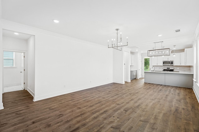 unfurnished living room featuring crown molding, sink, and hardwood / wood-style floors