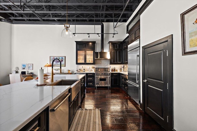 kitchen with dark wood-style flooring, high quality appliances, light stone countertops, a sink, and dark cabinets