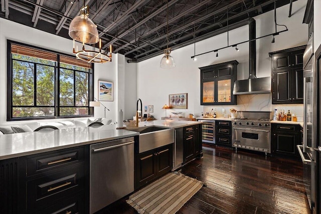 kitchen featuring beverage cooler, light countertops, dark cabinets, a sink, and appliances with stainless steel finishes