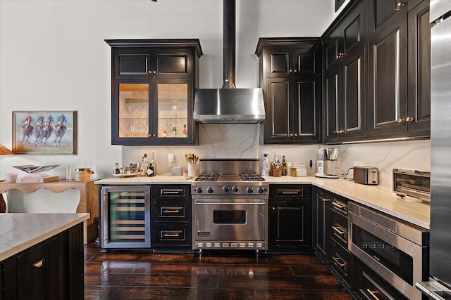 kitchen with wine cooler, wall chimney range hood, dark cabinetry, dark wood finished floors, and stainless steel appliances