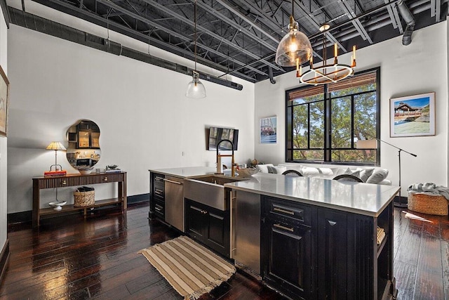 kitchen with stainless steel dishwasher, a sink, open floor plan, an inviting chandelier, and dark cabinetry