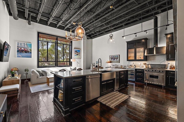 kitchen with a chandelier, dark cabinetry, a sink, dark wood finished floors, and stainless steel appliances