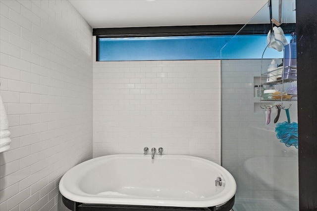 full bathroom with a freestanding tub and tile walls