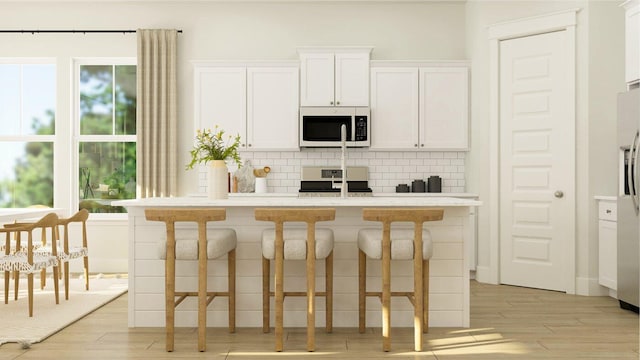 kitchen featuring white cabinets, a breakfast bar, decorative backsplash, and appliances with stainless steel finishes