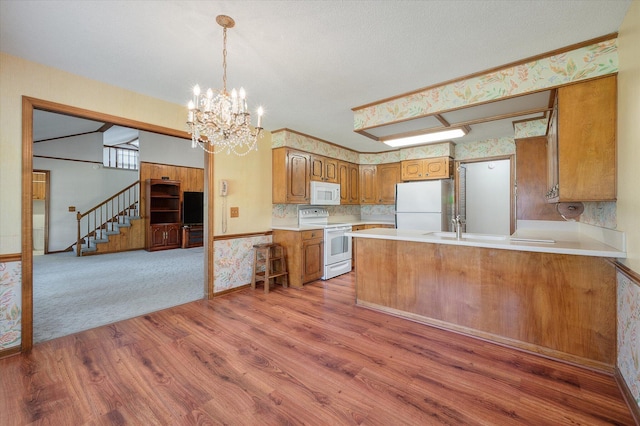 2912 Doncaster Dr, Charleston, SC 29414 - kitchen featuring white appliances, brown cabinets, wood finished floors, light countertops, and a peninsula