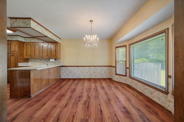 2912 Doncaster Dr, Charleston, SC 29414 - kitchen featuring wallpapered walls, brown cabinets, light wood-type flooring, a chandelier, and light countertops