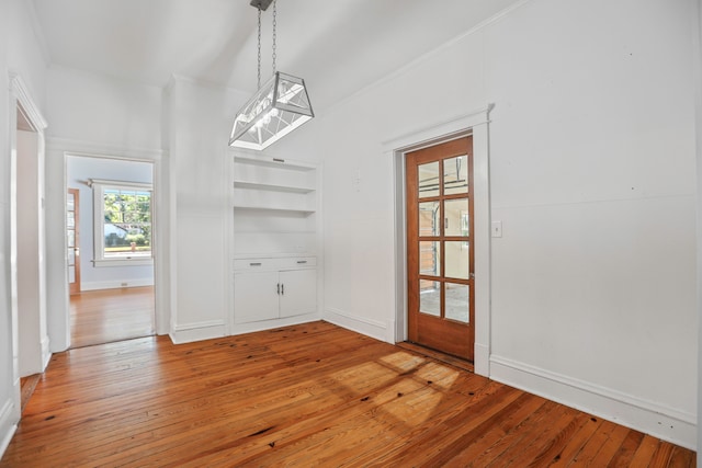 unfurnished dining area with wood-type flooring and built in features